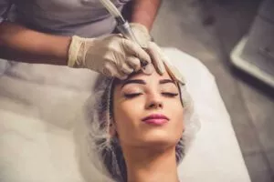 Beautiful young woman is getting face skin treatment. Doctor in medical gloves is undertaking the procedure using modern equipment